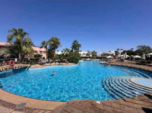 a large pool with blue water in a resort at 1 room apartment Delta in Sharm El Sheikh