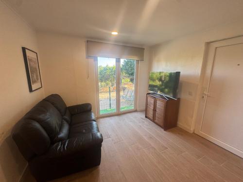 a living room with a leather couch and a television at Casa Oliveira in Silves