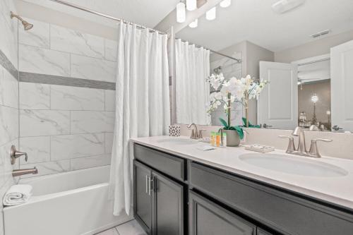 a bathroom with a sink and a shower and a tub at Near Disney 4BR with Private Pool in Kissimmee