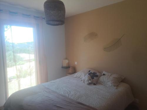 Un osito de peluche sentado en una cama en un dormitorio. en Nouveau villa T4 à Sotta entre mer et montagnes, en Sotta