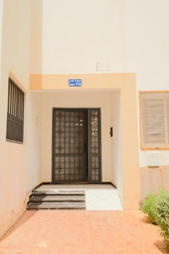 a building with a black door and a brick floor at Le Bohemian 2 chambres proche Plage des Nations avec Vue sur mer in Sidi Bouqnadel