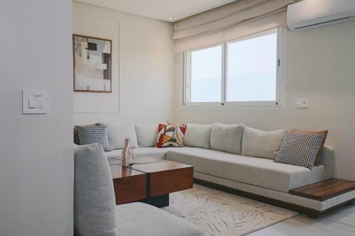 a living room with a couch and a table at Le Bohemian 2 chambres proche Plage des Nations avec Vue sur mer in Sidi Bouqnadel
