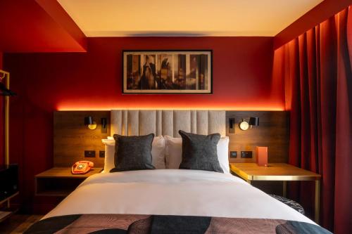 a bedroom with a large bed with red walls at Hotel Indigo Leeds by IHG in Leeds