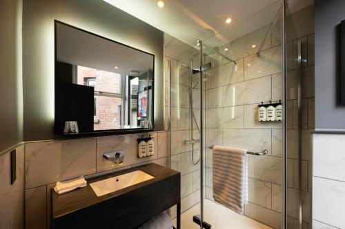 a bathroom with a sink and a shower with a mirror at Hotel Indigo Leeds by IHG in Leeds