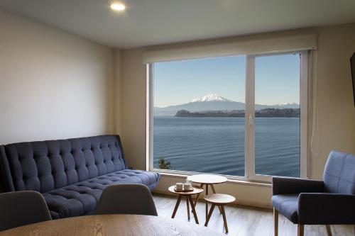 a living room with a couch and a large window at Apart Hotel Lake House - Puerto Varas in Puerto Varas