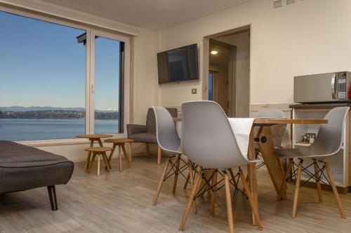 a living room with a table and chairs and a kitchen at Apart Hotel Lake House - Puerto Varas in Puerto Varas