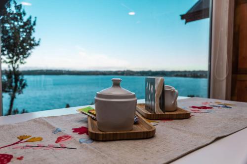 a table with two tea sets on a table with a window at Apart Hotel Lake House - Puerto Varas in Puerto Varas