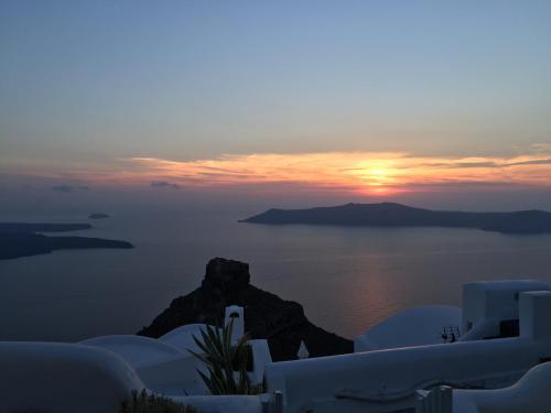 a sunset over the ocean with white buildings and the sky at Vallais Villa in Imerovigli