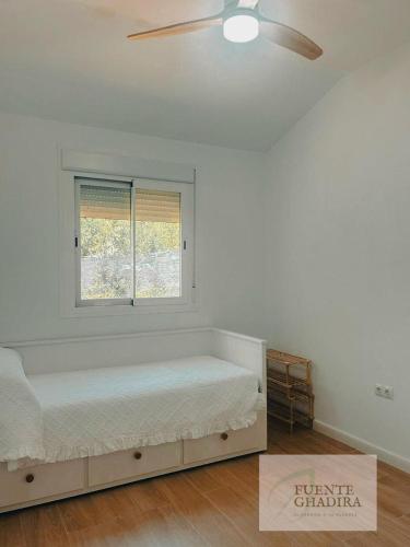 a white bedroom with a bed and a window at Fuente Ghadira Aracena in Aracena