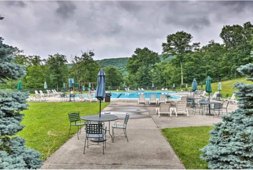 a table with chairs and umbrellas next to a pool at Whispering Pines Hot Tub, Porch & Waterparks in Tannersville