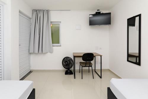 a white room with a table and a black chair at Casa Ecotrips Barra Funda - Hostel in Sao Paulo