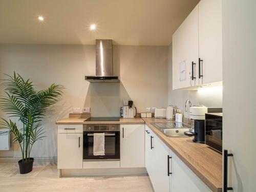 a kitchen with white cabinets and a stove top oven at Central Leeds Apartment near Arena and Victoria Quarter in Leeds