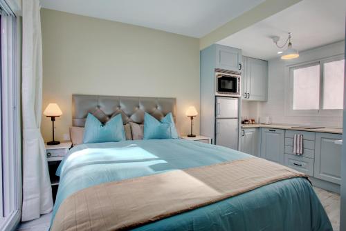 a bedroom with a large bed with blue pillows at Malaga Lodge Studio in Málaga
