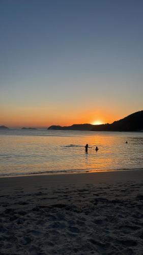 a person in the water at the beach at sunset at Chalé 400m Praia e Cachoeiras com Piscina Quente e Wifi in São Sebastião