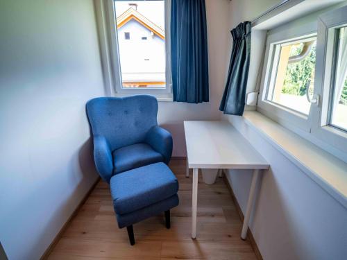 a blue chair and a table in a room with a window at Villa with terrace, sauna near the border triangle in Arnoldstein