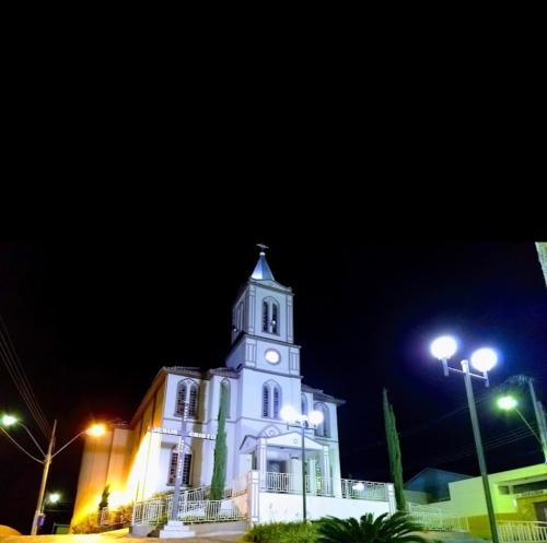 a white building with a clock tower at night at Hotel Rezende in Villa Nova de Resende