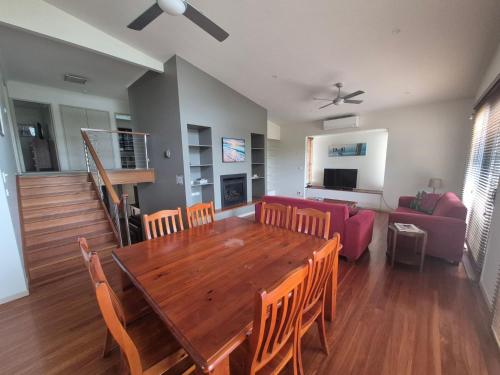 a dining room and living room with a wooden table and chairs at Seas The Day - Free Wifi, 180m Walk TO THE Beach in Vincentia