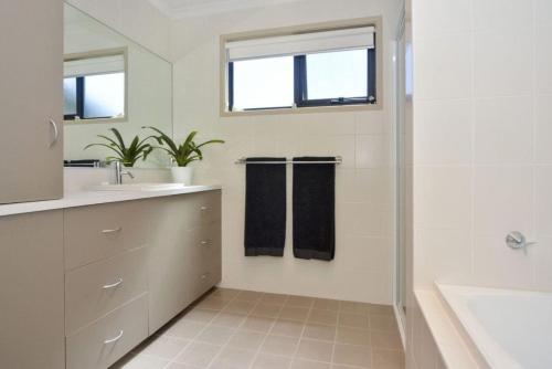 a white bathroom with a sink and a shower at Seas The Day - Free Wifi, 180m Walk TO THE Beach in Vincentia