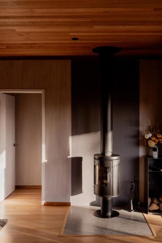 a stove in a room with a wooden ceiling at Spring Bay Mill in Triabunna