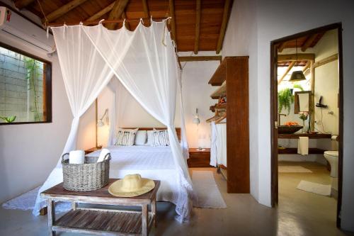 a bedroom with a canopy bed with a hat on a table at Trancoso House Casa de Temporada in Trancoso