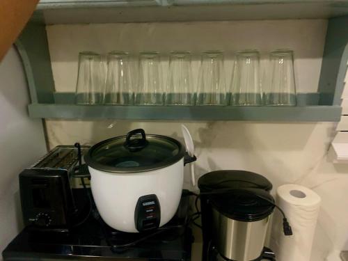 a pot on a stove with glasses on a shelf at Pedro's Heights 2 bedroom, 1 bathroom in Tumon