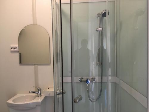 a shower with a glass door next to a sink at Karavanai "Aušroje" in Šventoji