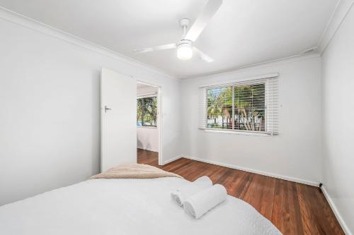 a white bedroom with a bed and two windows at Beach Shack No. 7 in Crescent Head