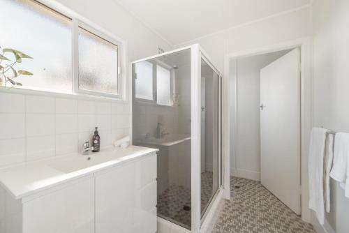 a white bathroom with a sink and a mirror at Beach Shack No. 6 in Crescent Head