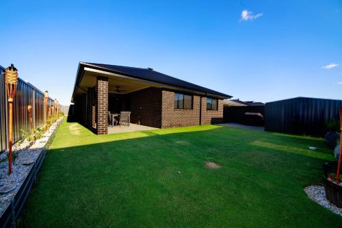 a house with a yard with green grass at Blackwood Retreat in Yarrawonga