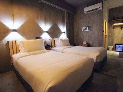 two beds in a hotel room with white sheets at Sukhum Rajamangala-Phatthanakan Rooms in Bangkok