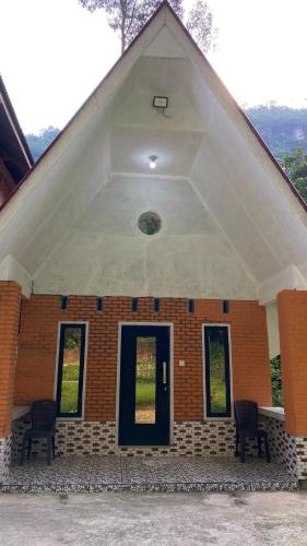 a brick house with a black door and chairs at Kenzona Homestay in Andalas