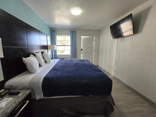 a hotel room with a large bed with a blue blanket at Ocean Holiday Motel in Daytona Beach