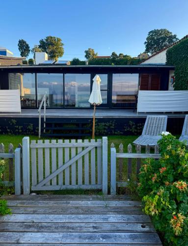 a house with a fence and two chairs and an umbrella at Beach House In Ålsgårde in Ålsgårde