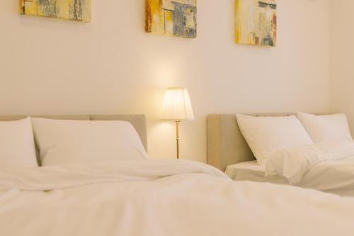 東京にあるPenthouse 8min walk to Shibuya Staのランプ付きの客室内の白いベッド2台