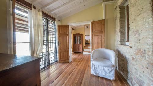a living room with a white chair and a stone wall at Da Bacchetta in Assisi