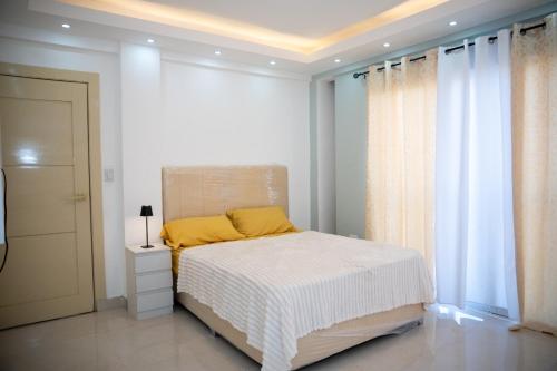 a white bedroom with a bed with a yellow pillow at Antonella 305 in Santo Domingo