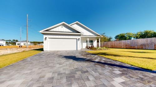 a house with a white garage on a driveway at New Construction - West End PCB - Gated Neighborhood - FLPCB63 in Panama City Beach