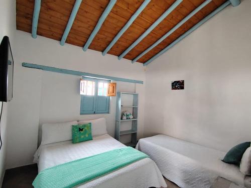 a bedroom with two beds in a white room at Hotel Villa Paz in Villa de Leyva