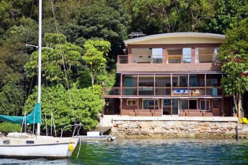 a large house with a boat in the water at Cottage Point - Paradise Found in Berowra