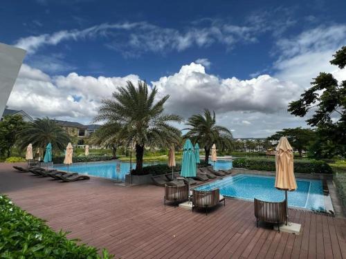 a resort pool with chairs and umbrellas and palm trees at Villa ATH Nova Word Phan Thiết in Bình Tú