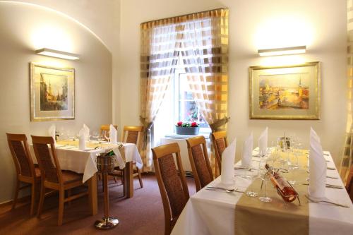 a dining room with tables and chairs and a window at Hotel Trinity in Olomouc