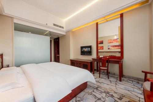 a bedroom with a white bed and a desk at Billions-Earn Hotel (near Guangdong Foshan Creative Park and China Ceramics City) in Foshan