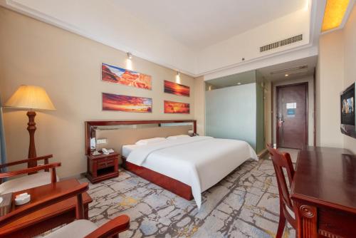 a bedroom with a white bed and a desk and a table at Billions-Earn Hotel (near Guangdong Foshan Creative Park and China Ceramics City) in Foshan