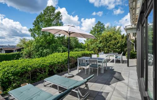 a patio with a table and chairs and an umbrella at Holiday Home Holbæk 39 With Hot Tub in Holbæk