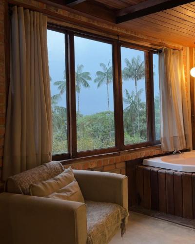 a living room with a tub and a couch and windows at Casa da Pedra Serrinha in Resende