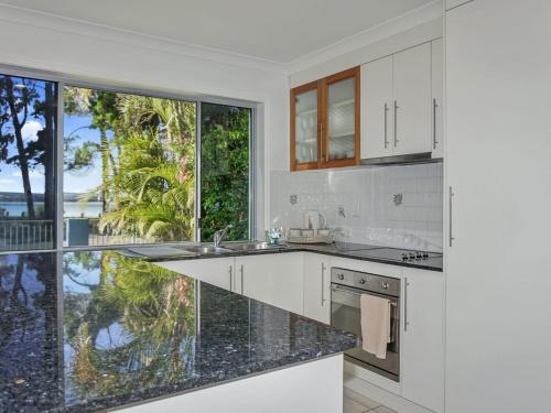 a kitchen with white cabinets and a large window at Welcome to Bay Views on Esplanade in Tin Can Bay