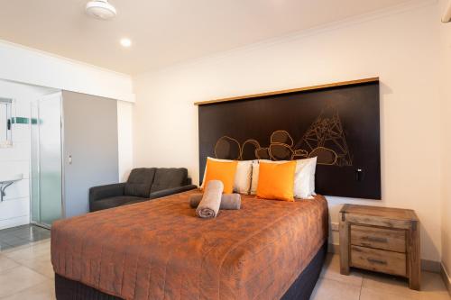 a bedroom with a large bed and a chair at Safari Lodge Motel in Tennant Creek