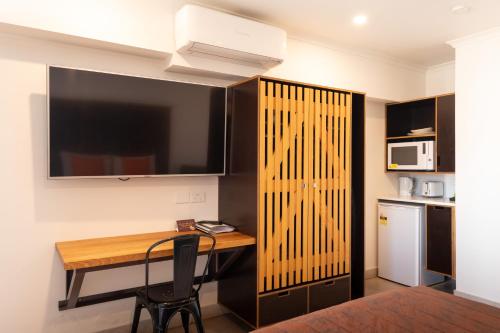 a room with a desk with a television and a kitchen at Safari Lodge Motel in Tennant Creek