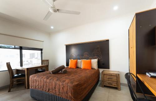 a bedroom with a bed with orange pillows and a desk at Safari Lodge Motel in Tennant Creek
