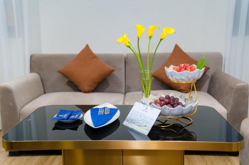 a coffee table with a vase of flowers and fruit on a couch at Sandals Mimosa in Da Lat